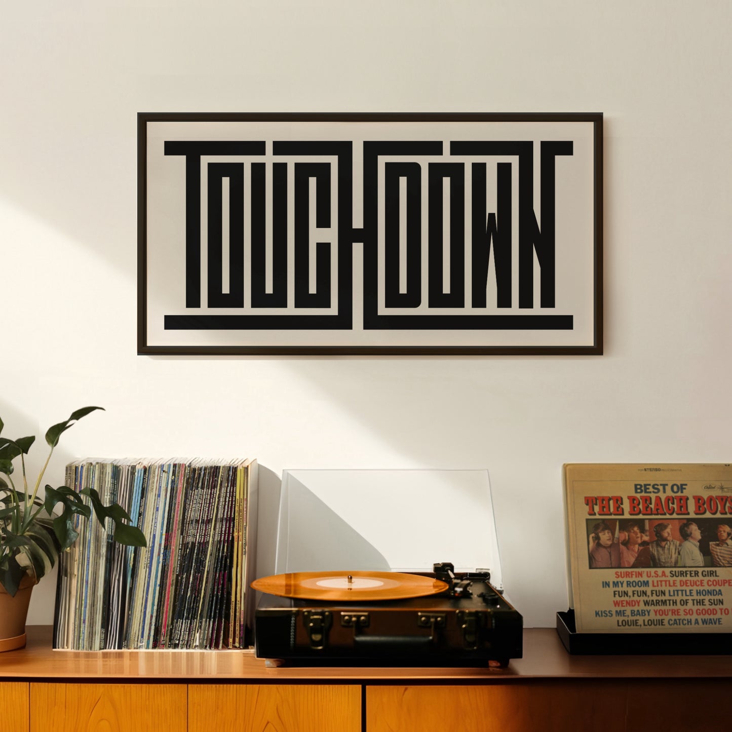 Retro Touchdown artwork above vintage record player on Mid-Century Modern furniture.