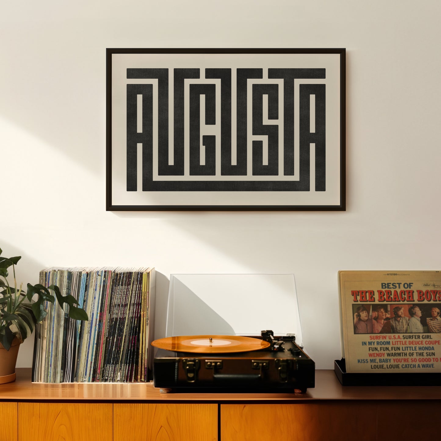 Retro Augusta artwork above vintage record player on Mid-Century Modern furniture.