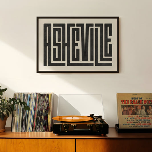 Retro Asheville artwork above vintage record player on Mid-Century Modern furniture.
