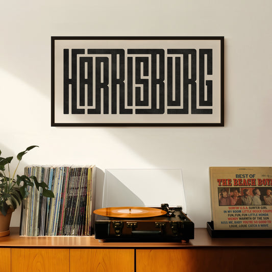 Retro Harrisburg artwork above vintage record player on Mid-Century Modern furniture.