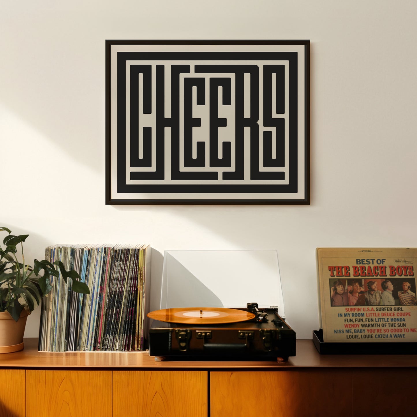 Retro Cheers artwork above vintage record player on Mid-Century Modern furniture.