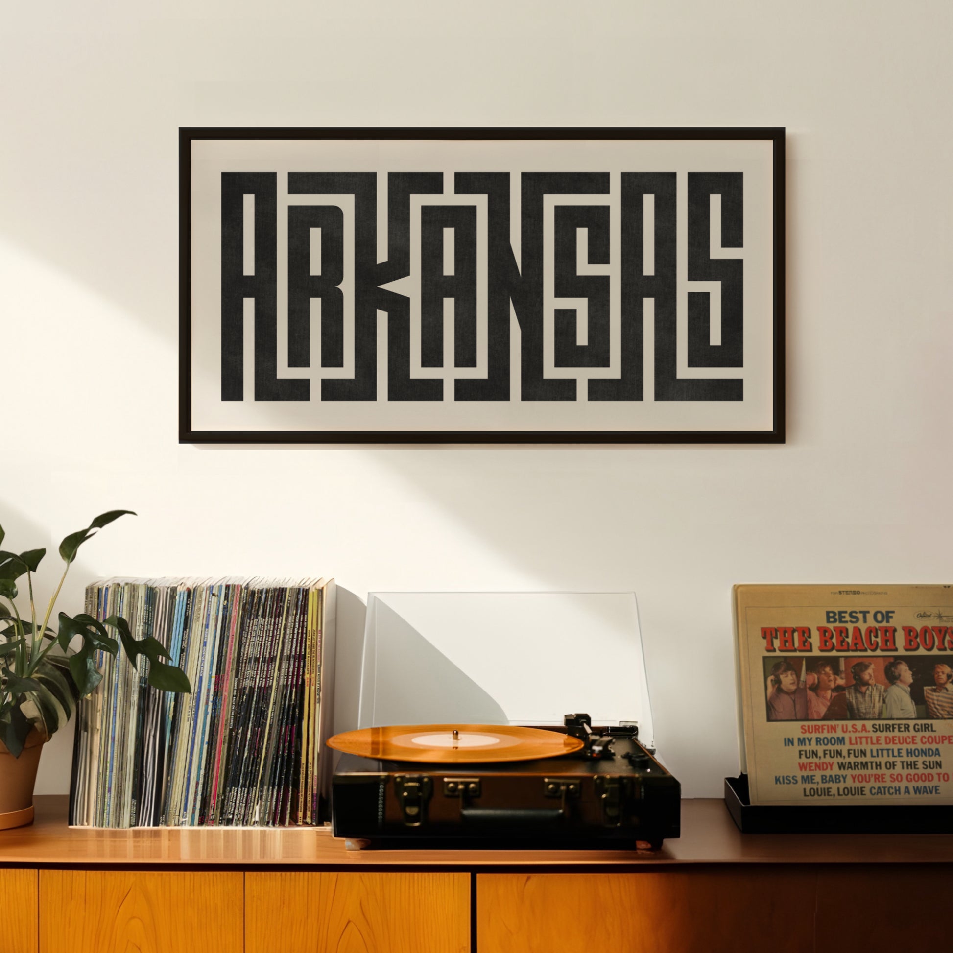 Retro Arkansas artwork above vintage record player on Mid-Century Modern furniture.