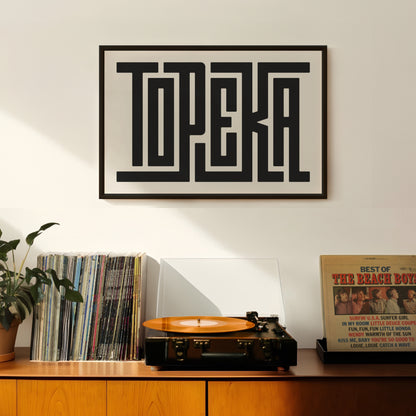 Retro Topeka artwork above vintage record player on Mid-Century Modern furniture.