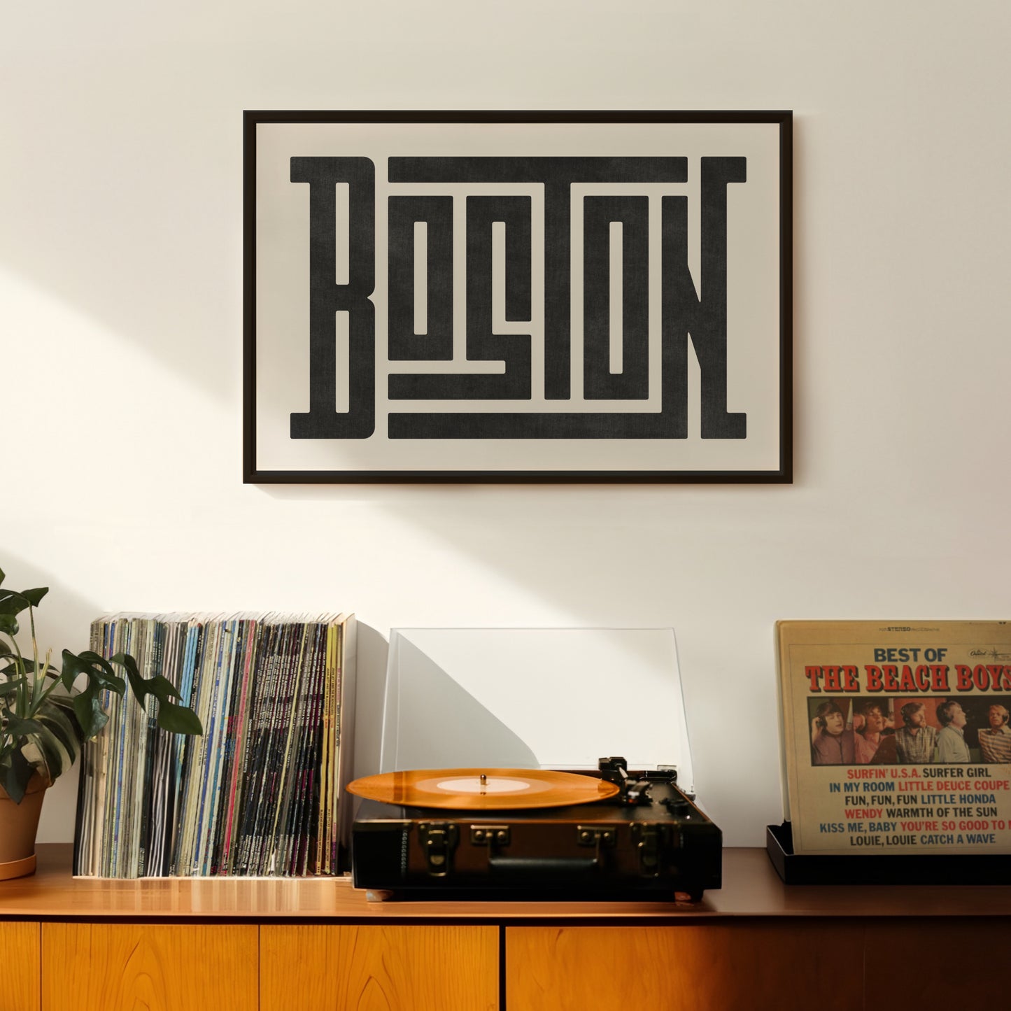 Retro Boston artwork above vintage record player on Mid-Century Modern furniture.