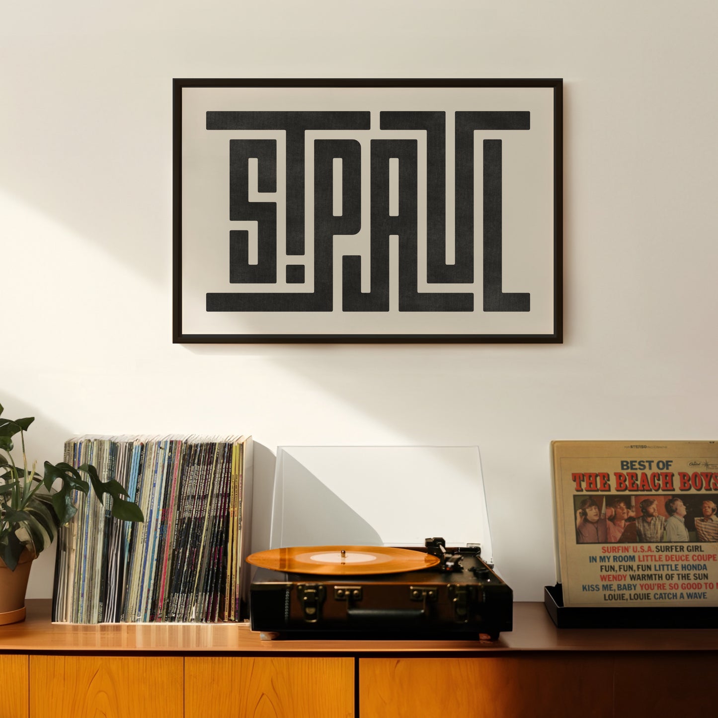 Retro Saint Paul artwork above vintage record player on Mid-Century Modern furniture.