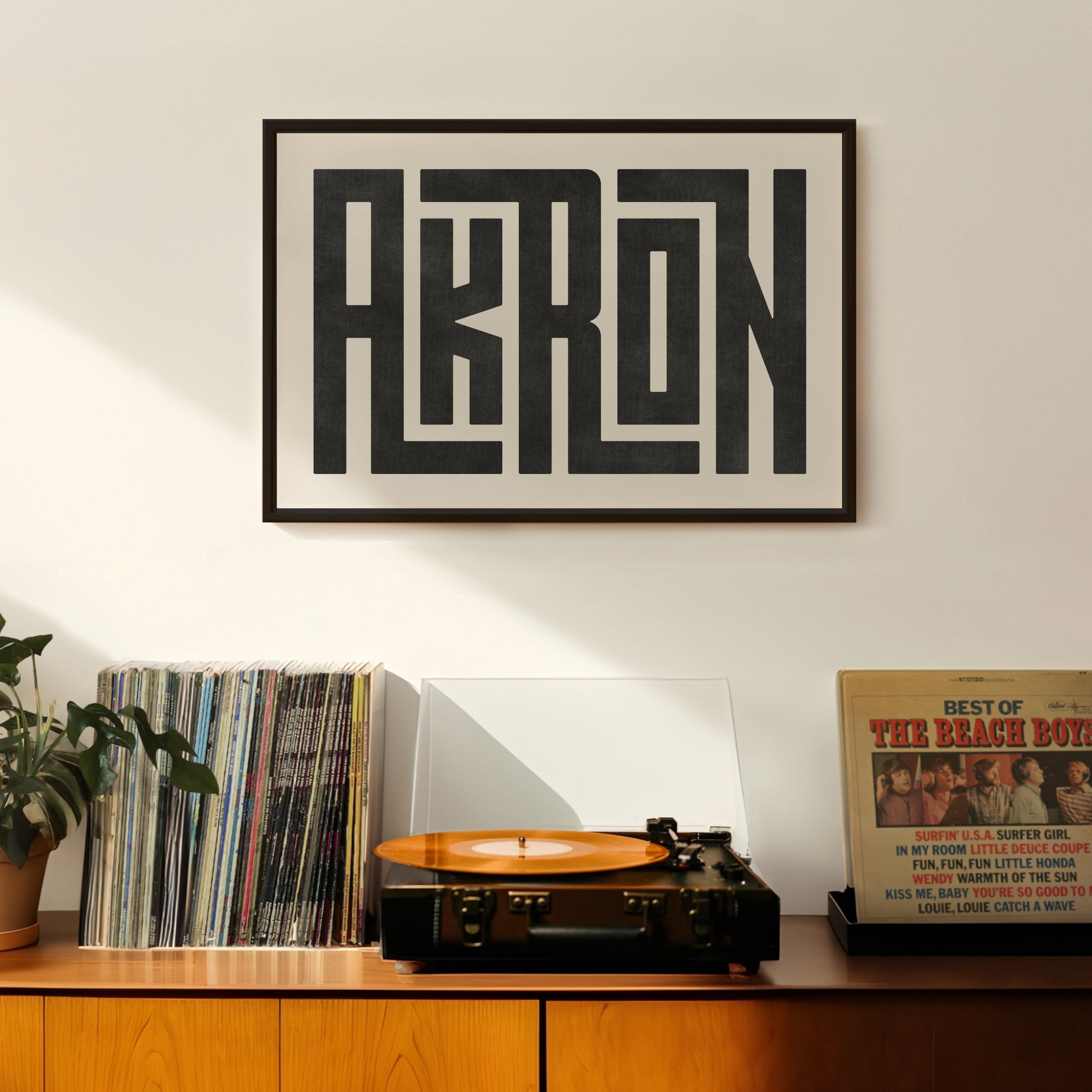 Retro Akron artwork above vintage record player on Mid-Century Modern furniture.