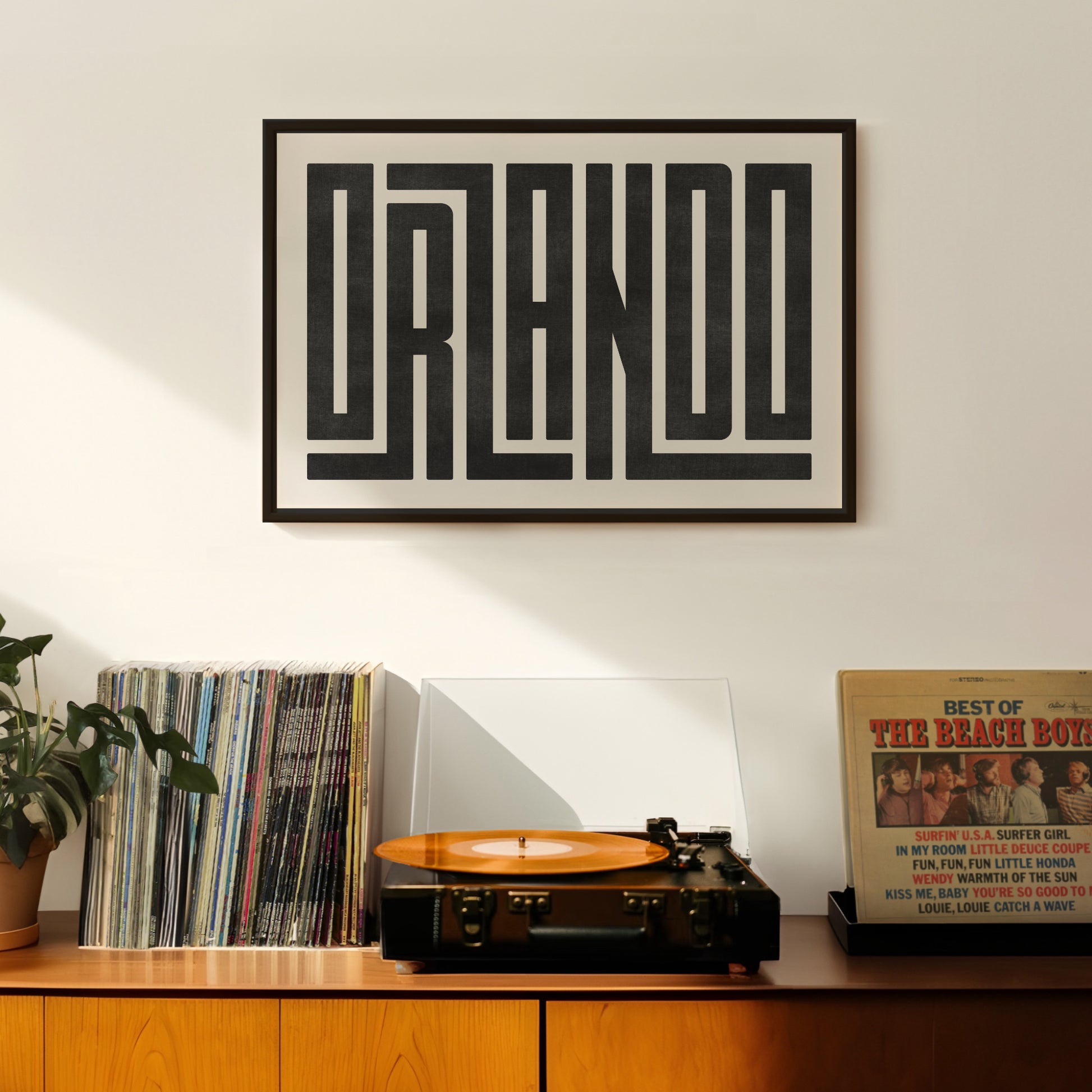 Retro Orlando artwork above vintage record player on Mid-Century Modern furniture.